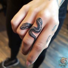 a person's hand with a tattoo on it and a snake on the ring