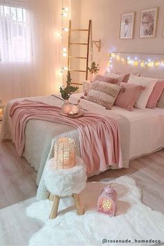 a bedroom decorated in pink and white with lights on the wall, bedding and rugs