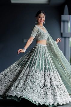 a woman in a green and white lehenga is posing for the camera with her arms outstretched