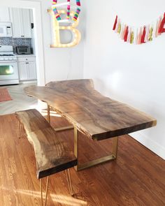 a wooden table with two benches next to it on a hard wood floor in front of a white wall