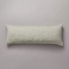 a white pillow with polka dots on the front and back, against a gray wall