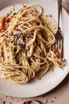 a white plate topped with pasta covered in sauce and parmesan cheese next to a fork