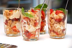 four glasses filled with different types of food on top of a wooden table next to each other