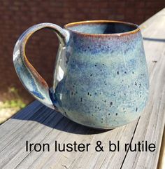 a blue and white mug sitting on top of a wooden table next to a brick wall