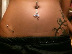 a woman's stomach with tattoos and piercings on her belly is seen in this undrecognized image