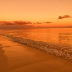 an orange sunset over the ocean with waves coming in