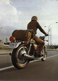 a man riding on the back of a motorcycle down a street