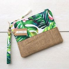 a green and white tropical print pouch with a name tag on the front, sitting on a wooden surface