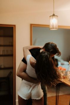 two women hug each other in front of a mirror