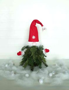 a santa hat sitting on top of a pile of pine branches with water droplets around it