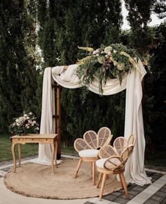 an outdoor wedding ceremony setup with white drapes and wicker chairs