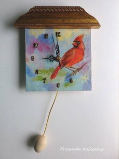 a clock with a red bird painted on it's face hanging from the wall