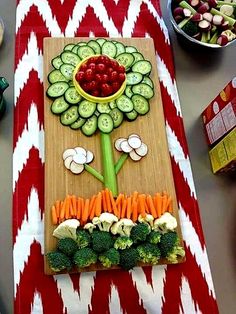 a table topped with vegetables and fruits on top of a wooden cutting board