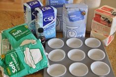 cupcakes, milk, flour and other baking supplies on a counter top with paper cups