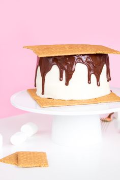 a white cake with chocolate drizzled on top and crackers next to it