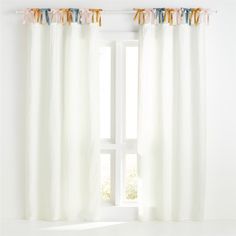 a white curtain with tassels hanging from it's sides in front of a window