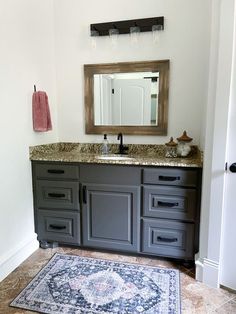 a bathroom with a rug, sink and mirror