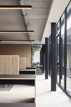 an empty office with wooden partitions and black tables in the center, along with large windows