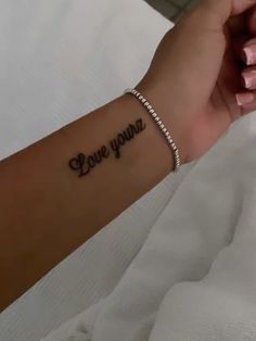 a woman's arm with the word love you on it and a small beaded bracelet