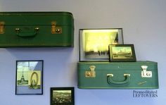 two green suitcases sitting next to each other on a wall with pictures and frames