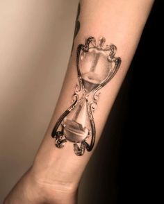 a tattoo on the arm of a woman with an hour and hourglass in it