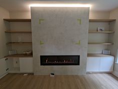 an empty living room with a fireplace and shelves