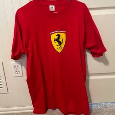 a red ferrari t - shirt hanging on a door with a white wall in the background