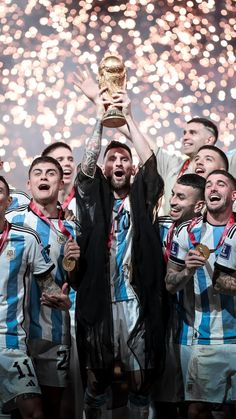 a group of men standing next to each other holding up a trophy in front of fireworks