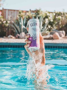 someone is holding up a can of water in the pool