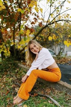 a woman sitting on the ground in an orange pants