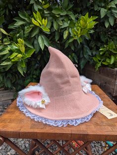 Are you a witchy cat? Or a kitty witch? Either way, this pink hat is purrfect, featuring white ruffle lace trim and super soft fluffy white ears.  This hat will keep you shaded on warm days, and warm on those cool fall evenings. Please note that colors may differ slightly due to differences in screen calibration. This lower profile hat is about 10" high making it great for dress up or everyday wear, and is sure to turn heads.  The brim diameter is about 14" and just enough to provide some shade on those warmer days.   The hat has a sloped shape that allows it to fit most folks comfortably. Materials: wool blend Care: Spot clean as needed with damp cloth Please note that this item ships folded flat.  It will regain its shape with wear. Pink Halloween Costume Hat, Pink Cat Ears Hat For Winter, Pink Winter Hat With Cat Ears, Cute Halloween Cap Hat, Cute Halloween Costume Hats And Headpieces, Whimsical Adjustable Cat Ears Hats, Whimsical Adjustable Hats With Cat Ears, Cute Pink Costume Hats And Headpieces, Cute Cat Ears Hat