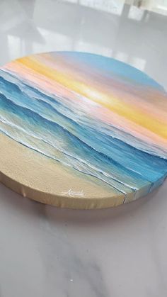 a painted plate sitting on top of a white counter next to a window with an ocean view