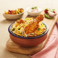 a bowl filled with chicken and rice on top of a wooden table