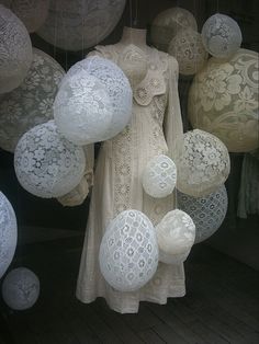 there are many white balls hanging from the ceiling in front of a woman's dress