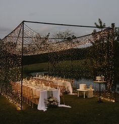 an outdoor dining area with tables and chairs covered in fairy lights