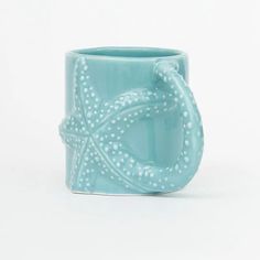 a blue ceramic mug with a starfish design on the front and bottom, sitting on a white surface