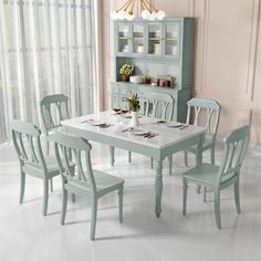 a dining room table with chairs and a china cabinet in the back ground, next to a window