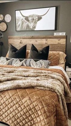 a bed with brown and black pillows in a bedroom next to a painting on the wall