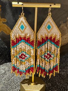 Beaded earrings with fringe made by hand in the USA using Miyuki Delica 11/0 seed beads and 14k gold filled 20 gauge ear wires.  The beads are woven with a needle and thread in a brick stitch and fringe technique. Each pair takes several hours to complete.  Please do not swim or shower while wearing. *pattern by HandMadeInUA Gold Heishi Beads Earrings, Traditional Beaded Earrings With Fringe For Festivals, Traditional Beaded Fringe Earrings For Festival, Gold Dangling Heishi Beads Earrings, Artisan Gold Earrings With Beaded Fringe, Artisan Beaded Earrings With Fringe, Gold Artisan Beaded Fringe Earrings, Traditional Handwoven Gold Beaded Earrings, Traditional Gold Handwoven Beaded Earrings