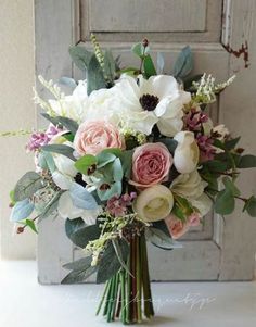 a bouquet of flowers sitting on top of a table next to an old wooden door