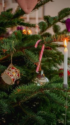 a christmas tree with ornaments hanging from it's branches and candles in the middle