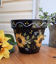 two sunflowers are sitting on a table next to a potted planter