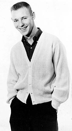 an old black and white photo of a young man wearing a cardigan over a sweater