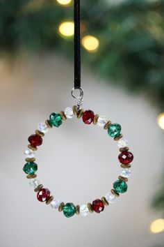 a christmas ornament hanging from a tree with lights in the background and a red, green and white bead