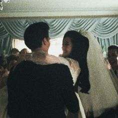 a bride and groom hug each other in front of a group of people at a wedding