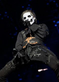 a man with white face paint on his face and black pants, standing in the air