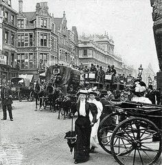 an old black and white photo of horse drawn carriages on a city street with people standing around