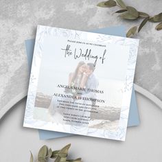 a wedding card on top of a plate next to flowers and greenery with the words, the wedding of