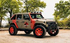 a jeep with orange rims parked in front of some trees