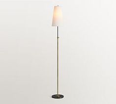 a floor lamp with a white shade on it's side and a black base